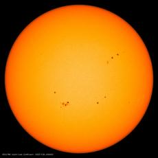 来自太阳动力学观测站任务的图像显示，太阳盘上有多个太阳黑子，与周围环境相比，这些黑子看起来很暗。学分：HMI/SDO/NASA
