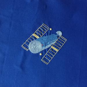 The Hubble Space Telescope embroidered in yellow, grey and blue threads on a blue background.