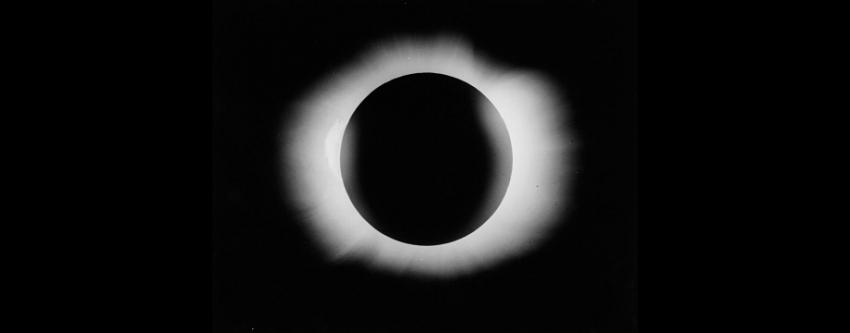 The Sun is a big black circle with bursts of light protruding around its edge as it is eclipsed by the Moon.