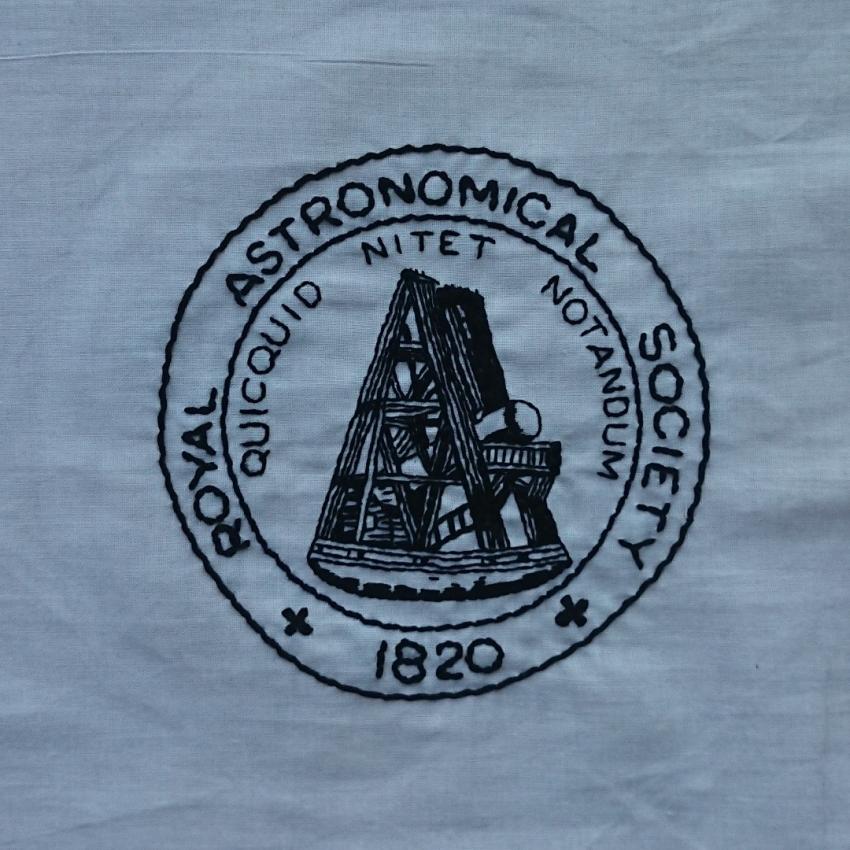 Old RAS logo embroidered in black thread on white background.