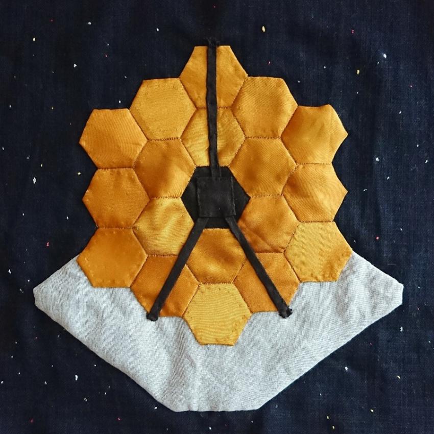 The James Webb Space Telescope made with appliqued fabric and embroidery.