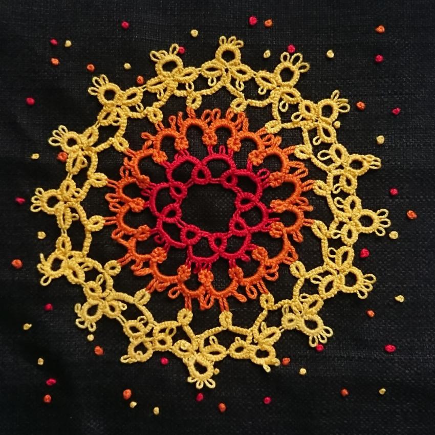 The inner layers of a star (red in the centre, orange and then yellow) made using a lace technique called tatting.