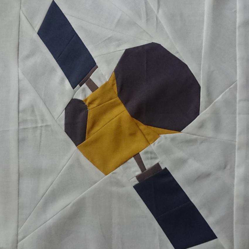 The Transiting Exoplanet Survey Satellite (TESS) created using yellow and grey pieces of fabric on a white background.