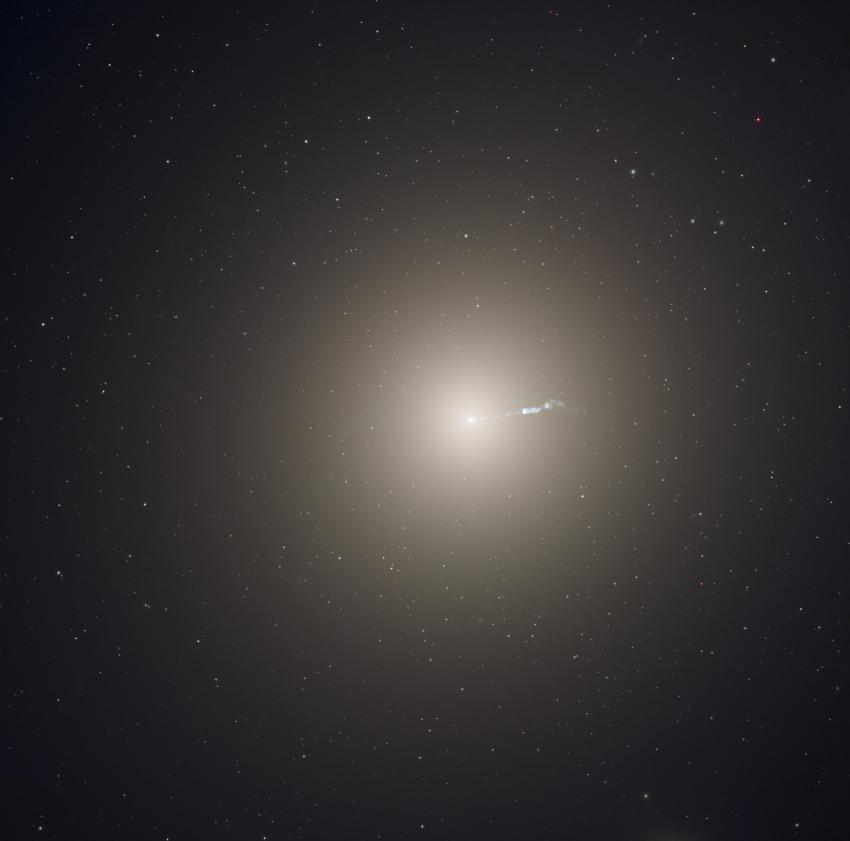 A bright white galaxy that is round in shape, glowing against the darkness of space.
