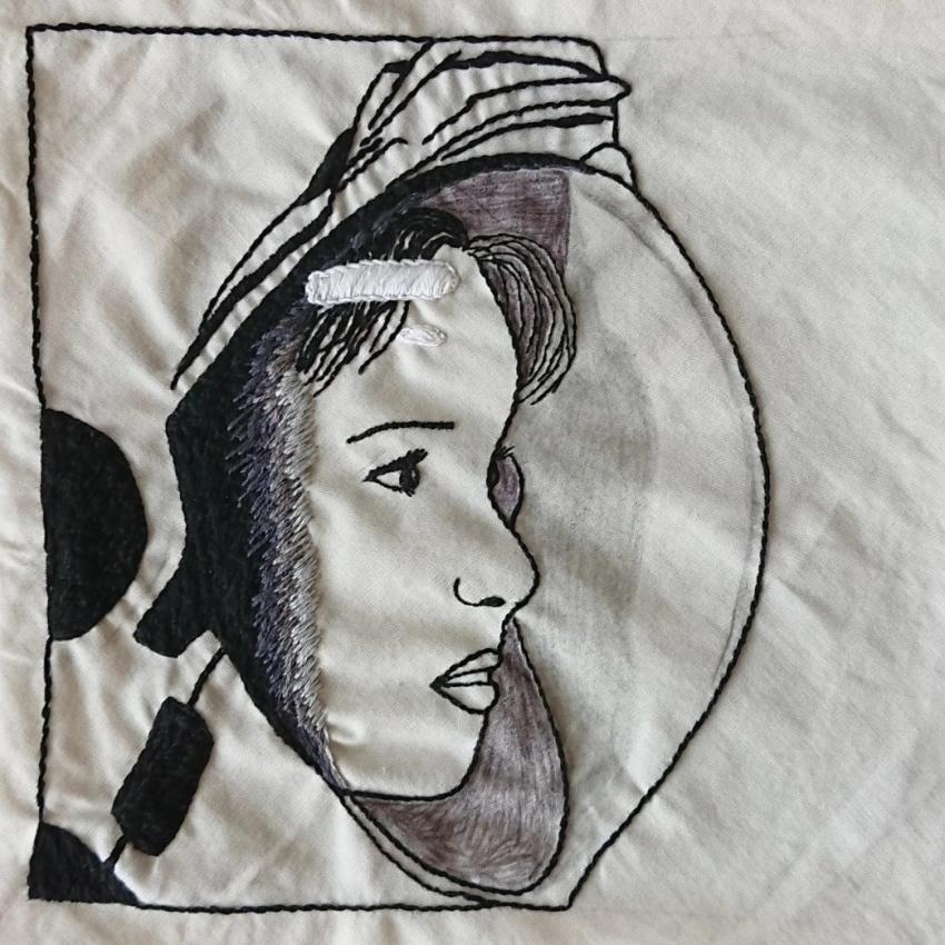 Embroidered outline of an astronaut's face and helmet in profile view. Stitched in black and grey threads on a white background.