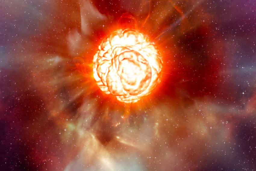 a large orange star is seen exploding, with layers of orange fiery looking material being blown outwards as well as rays of high energy.