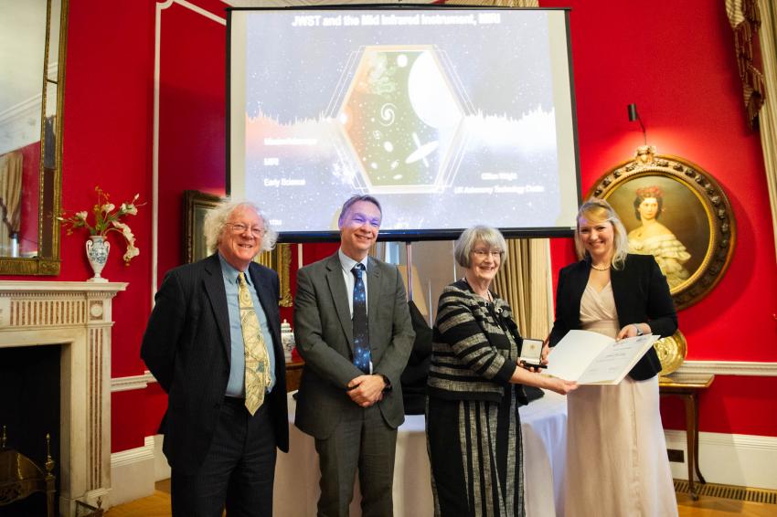 Professor Michael Kramer, Professor Mike Edmunds, Professor Gillian Wright and Professor Stefanie Walch-Gassner stand side by side in front of a podum. Professor Walch-Gassner is handing a certificate and a medal in a box to Professor Wright. All are smiling for the camera.
