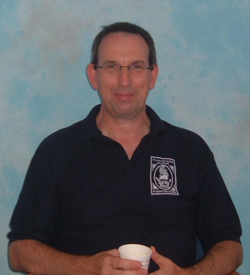 A picture of Prof. Mike Lockwood in a dark blue polo shirt holding a paper cup. 