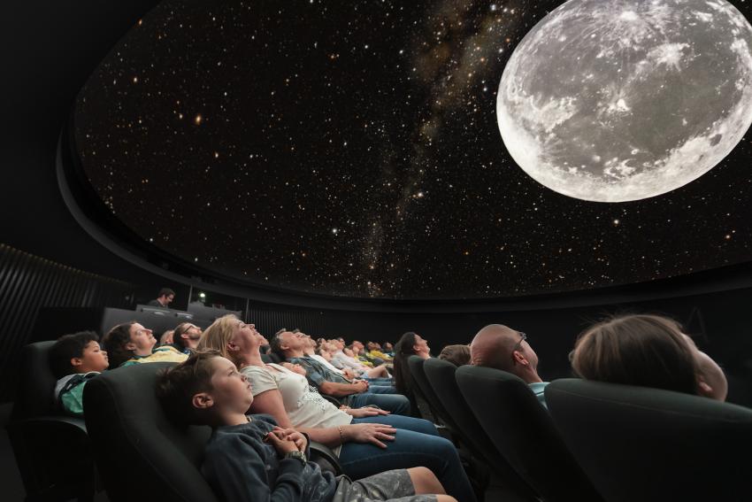 People watching the Moon at a planetarium show.