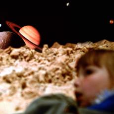 A young girl inside a planetarium in awe of the view if the solar system.