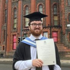 Portrait of Bradley Lewis holding his degree certificate