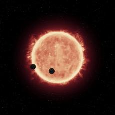 This artist's impression shows two Earth-sized worlds passing in front of their parent red dwarf star in the TRAPPIST-1 system 40 light-years away.