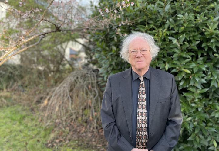 Image of Professor Mike Edmunds standing in front of trees and shrubs, smiling at the camera.