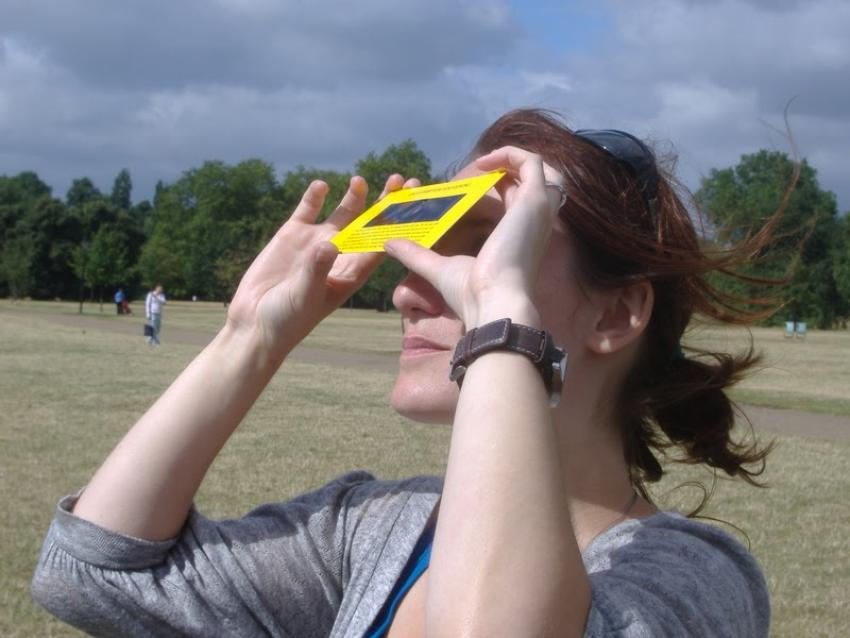 A woman using eclipse shades, certified to safety standards, to view a solar eclipse.