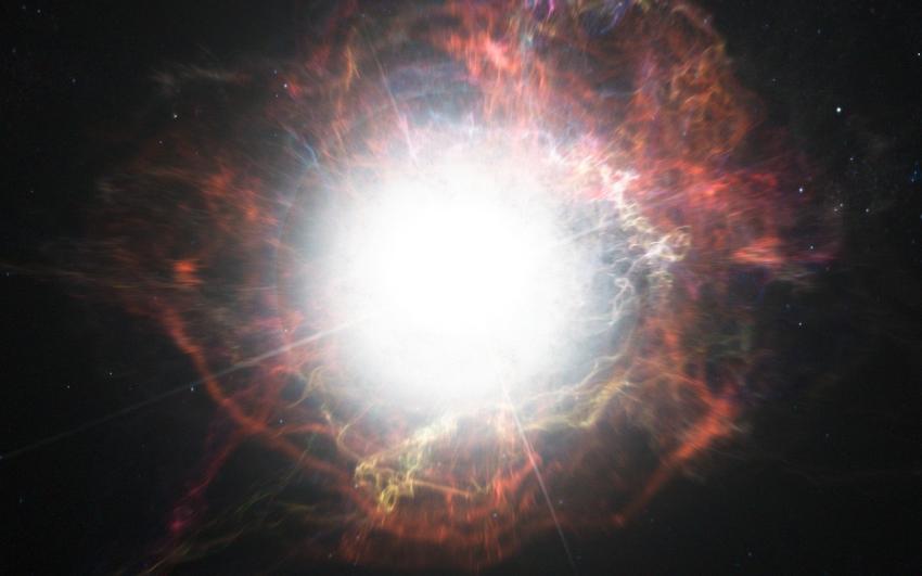 A bright, white light in the middle of the image surrounded by red hued filament structures and clouds.