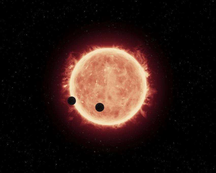 This artist's impression shows two Earth-sized worlds passing in front of their parent red dwarf star in the TRAPPIST-1 system 40 light-years away.